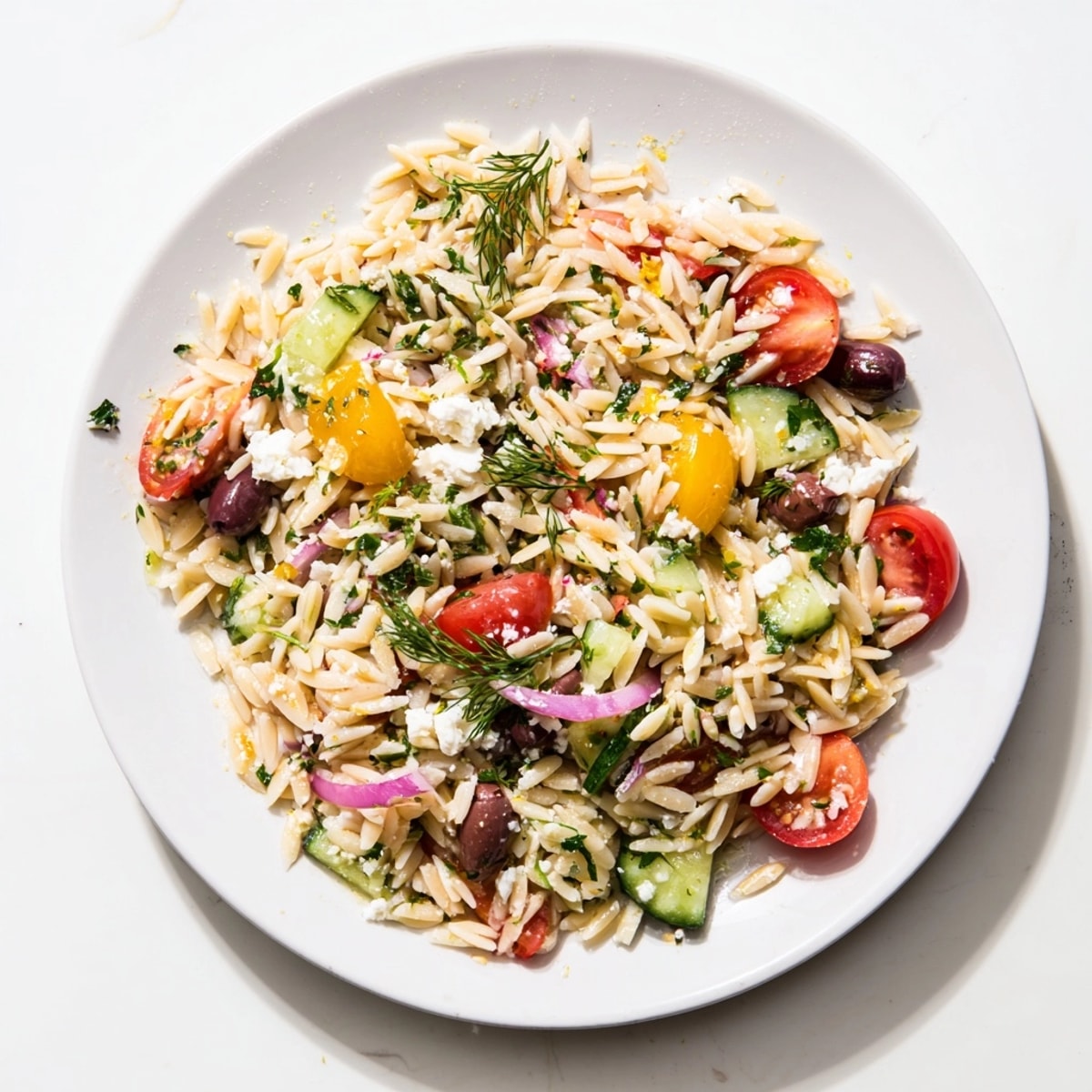 Freshly made Greek Orzo with Feta and Olives, with summer vegetables, ready to eat.