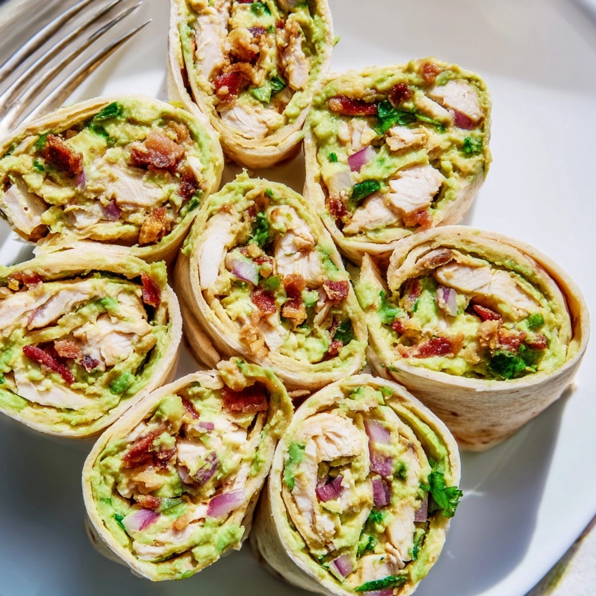 Delicious Avocado Chicken Bacon Pinwheels ready to be sliced, showing the creamy filling.