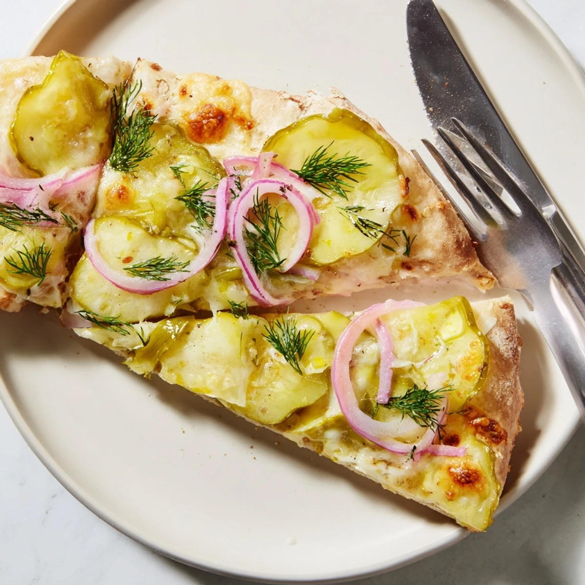 Creamy pickle pizza topped with mozzarella and crisp dill pickles, ready to enjoy.  