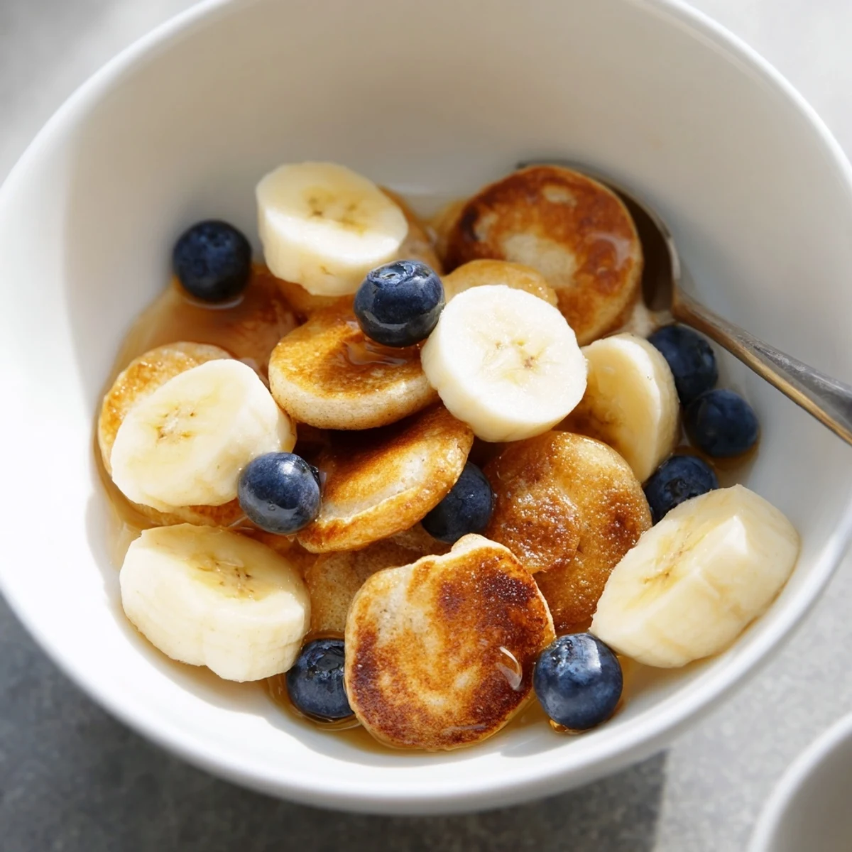 Mini pancake cereal topped with fresh berries and syrup, a delightful breakfast treat.  
