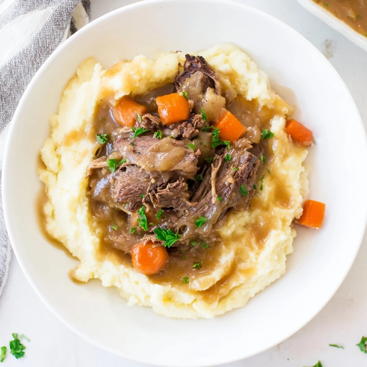 Fork-tender pot roast, served with rich gravy and fluffy mashed potatoes, is a warm, comforting dinner.