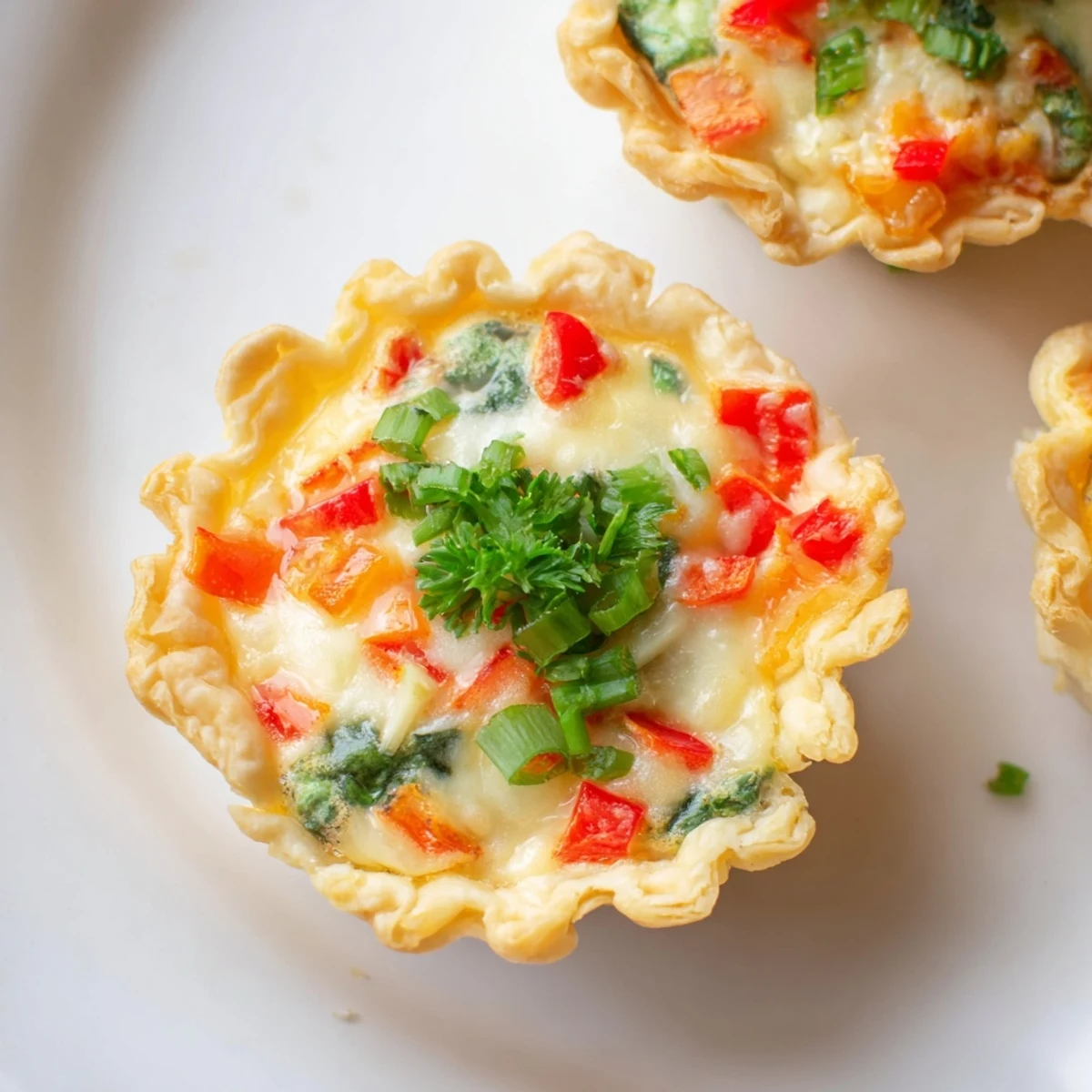 Golden-brown Easy Festive Mini Quiche Cups, savory and filled with cheese and vegetables.