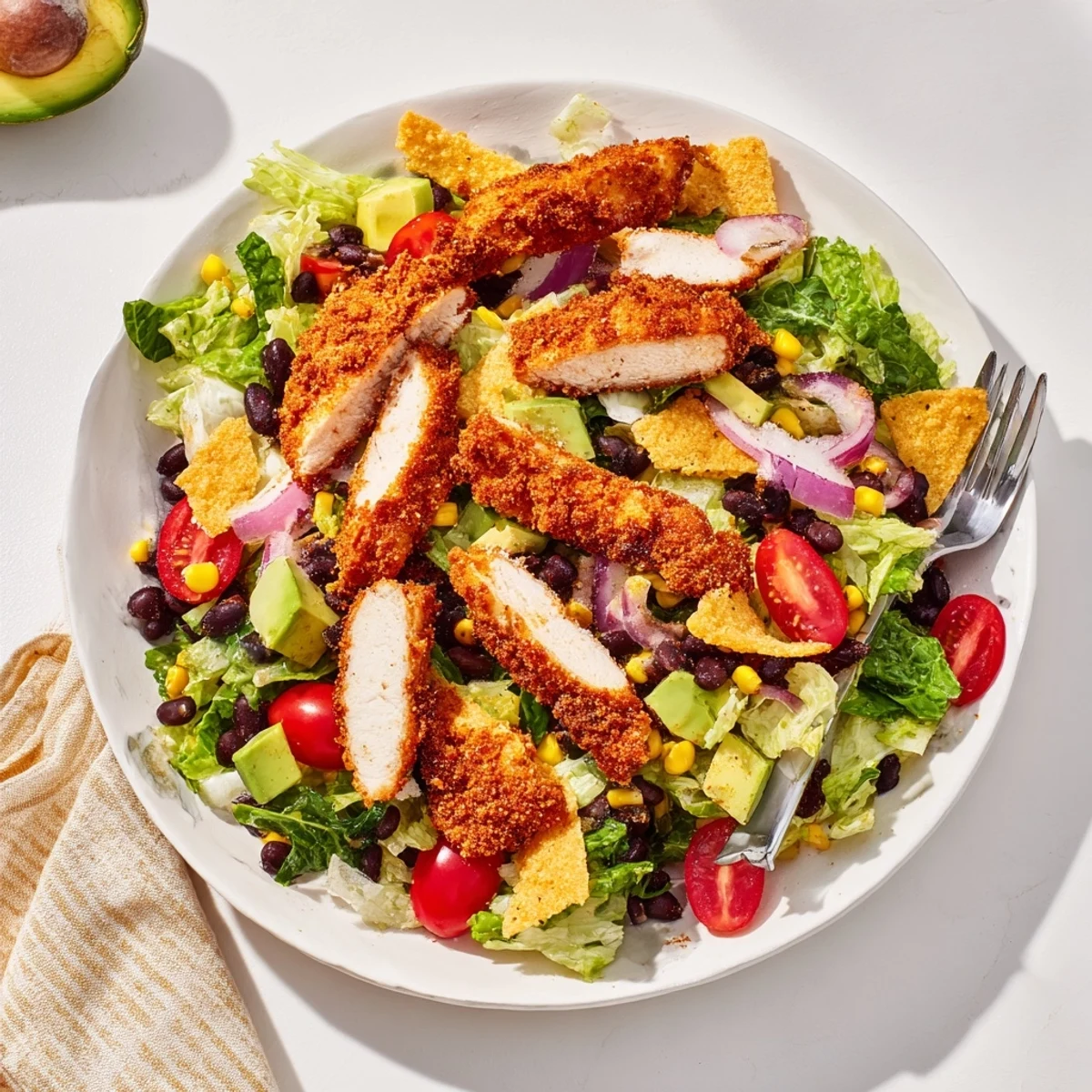 A close-up view of the Crispy Chicken Taco Salad shows creamy salsa ranch dressing drizzled over crunchy tortilla strips and diced avocado.
