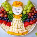 A charming Cherub Angel Snack Tray, filled with vibrant fruits and cheeses, perfect for a baby shower.