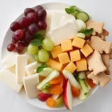 A vibrant Gentle Giant Elephant Cracker Board featuring cheddar, grapes, and a creamy brie cheese selection.