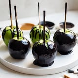 This Poison Apple recipe presents glistening, black candied apples surrounded by chocolate and spooky sweets for guests.