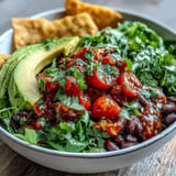 Colorful vegan taco bowl layered with seasoned black beans, avocado, and corn.
