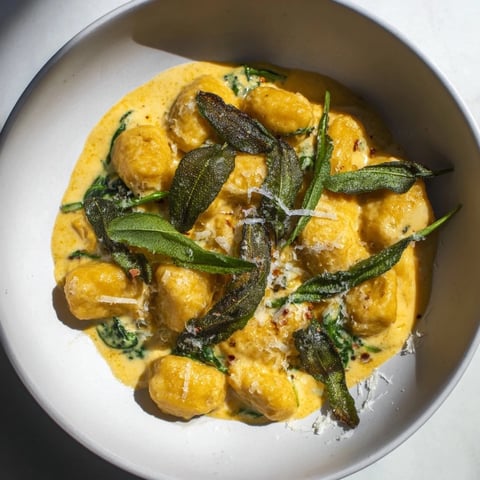 Golden One-Pot Creamy Pumpkin Sage Gnocchi Pasta, ready to serve with crispy sage and extra Parmesan.