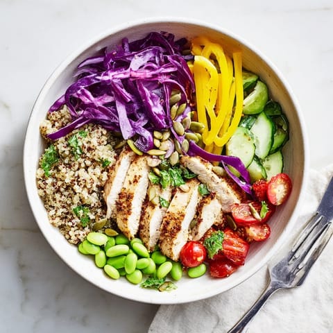 Sliced chicken rests atop Healthy Meal-Prep Bowls, garnished with fresh parsley and pumpkin seeds.  