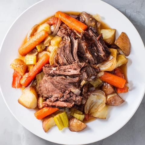 Vibrant image shows a steaming plate of comforting Sunday Pot Roast with hearty veggies and rich gravy.