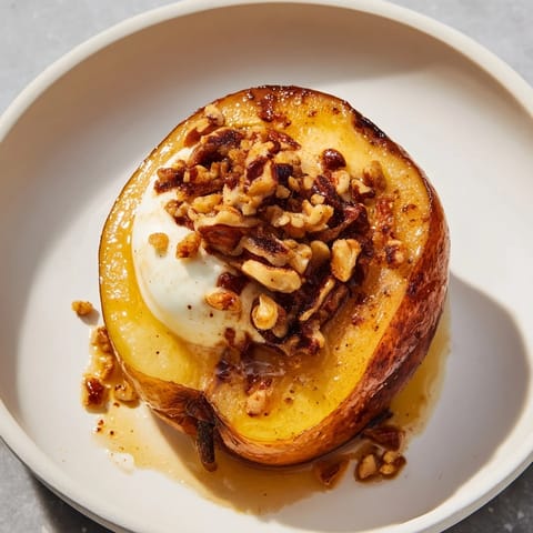 Golden-brown roasted pears, topped with walnuts and creamy Greek yogurt, featuring cinnamon flavors.