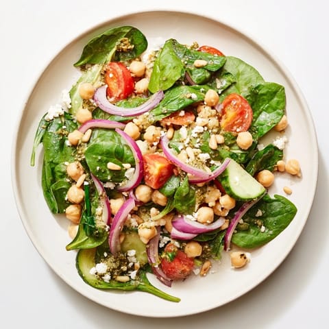 This delicious Pesto Chickpea and Spinach Salad features bright red tomatoes and fresh green spinach, ready to enjoy.