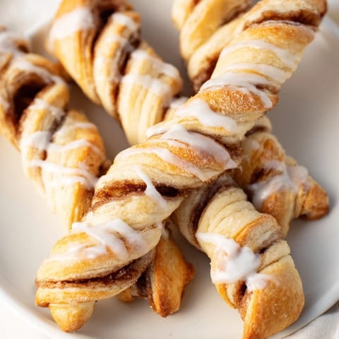 These Air-Fryer Cinnamon Roll Twists are flaky and sweet, topped with a creamy vanilla glaze, perfect for sharing.