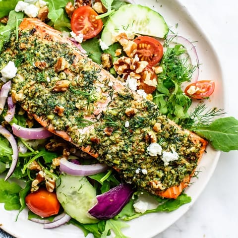 Flaky, baked herb-crusted salmon atop colorful salad, a light and healthy dinner option.