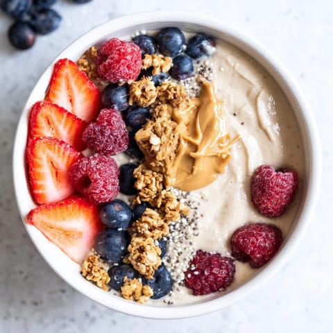 Thick and creamy Protein Ice Cream Bowls with visible mixed berries and a drizzle of nut butter.