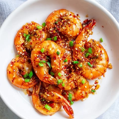 Golden-brown Korean garlic butter shrimp, ready to serve, sprinkled with sesame seeds and scallions.