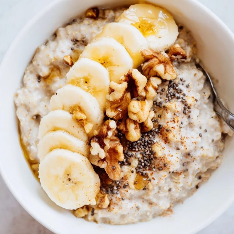 A close-up of finished Microwave Banana Oats, garnished with extra banana and nuts, warm and ready.