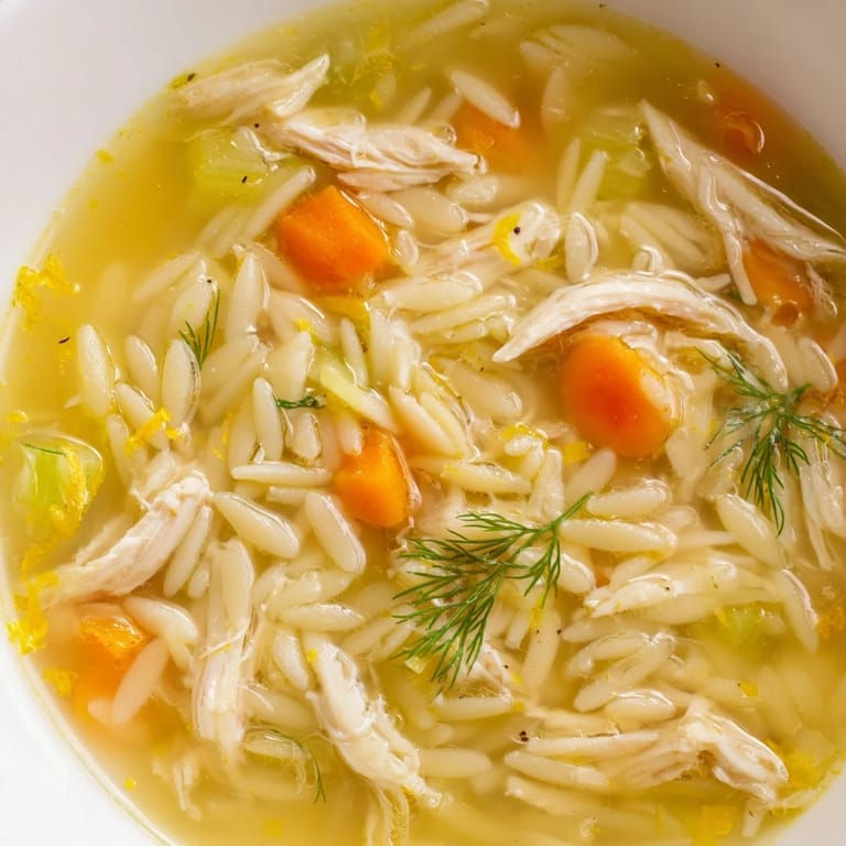 Comforting Chicken Lemon Orzo Soup ready to serve, garnished with parsley and lemon wedges on a cozy kitchen table.