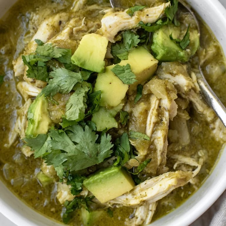 A hearty bowl of Chicken Chili Verde garnished with sliced radishes and lime wedges, served alongside warm corn tortillas for dipping.  