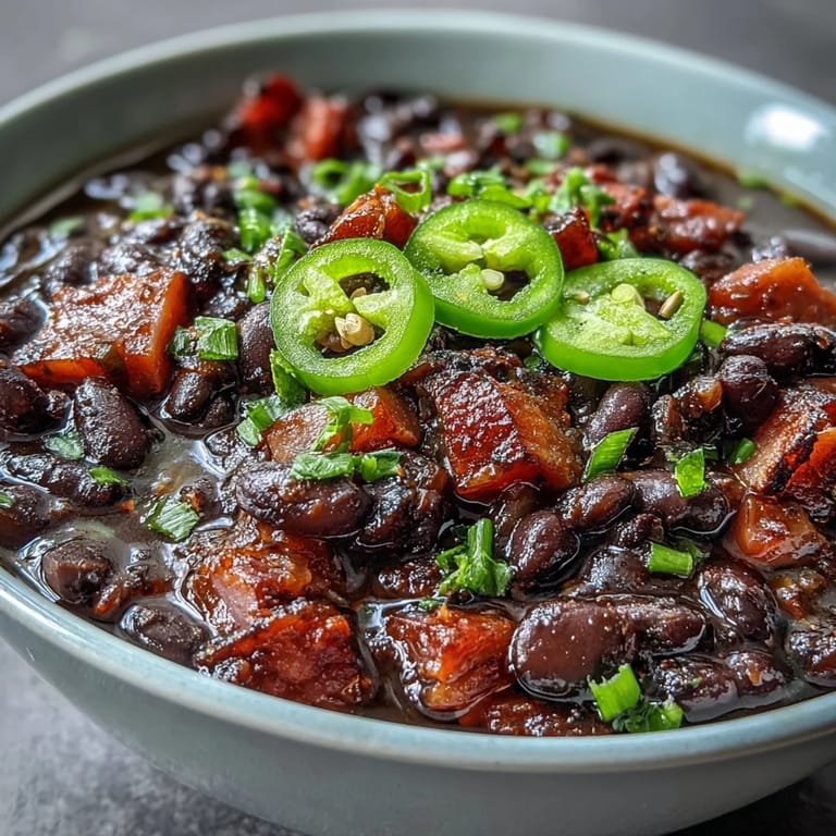 Spicy black bean and ham soup with jalapeños, garnished with cilantro and served with crusty bread for dipping.