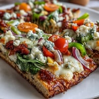 Vibrant St. Patricks Day Rainbow Veggie Flatbread Pizza with colorful bell peppers, tomatoes, and fresh herbs on a crisp naan base.