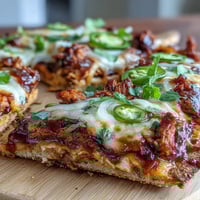 A golden BBQ chicken flatbread pizza with melted mozzarella, red onions, and fresh cilantro on a crisp crust.  